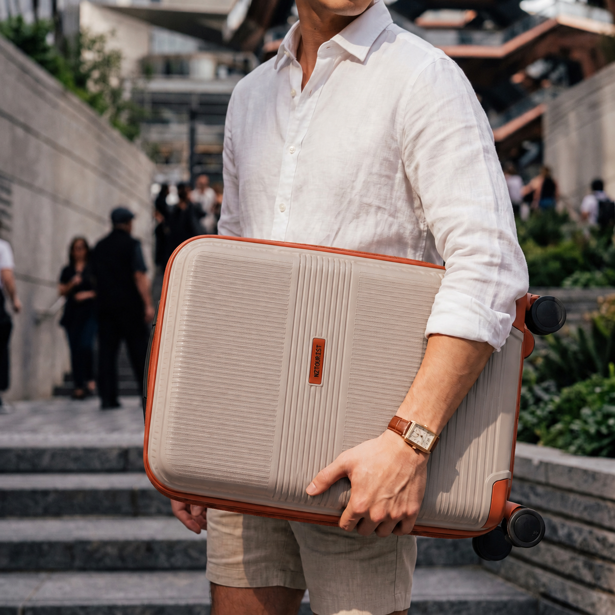 Man carrying a beige carry on suitcase with tan trim under his arm on stone steps