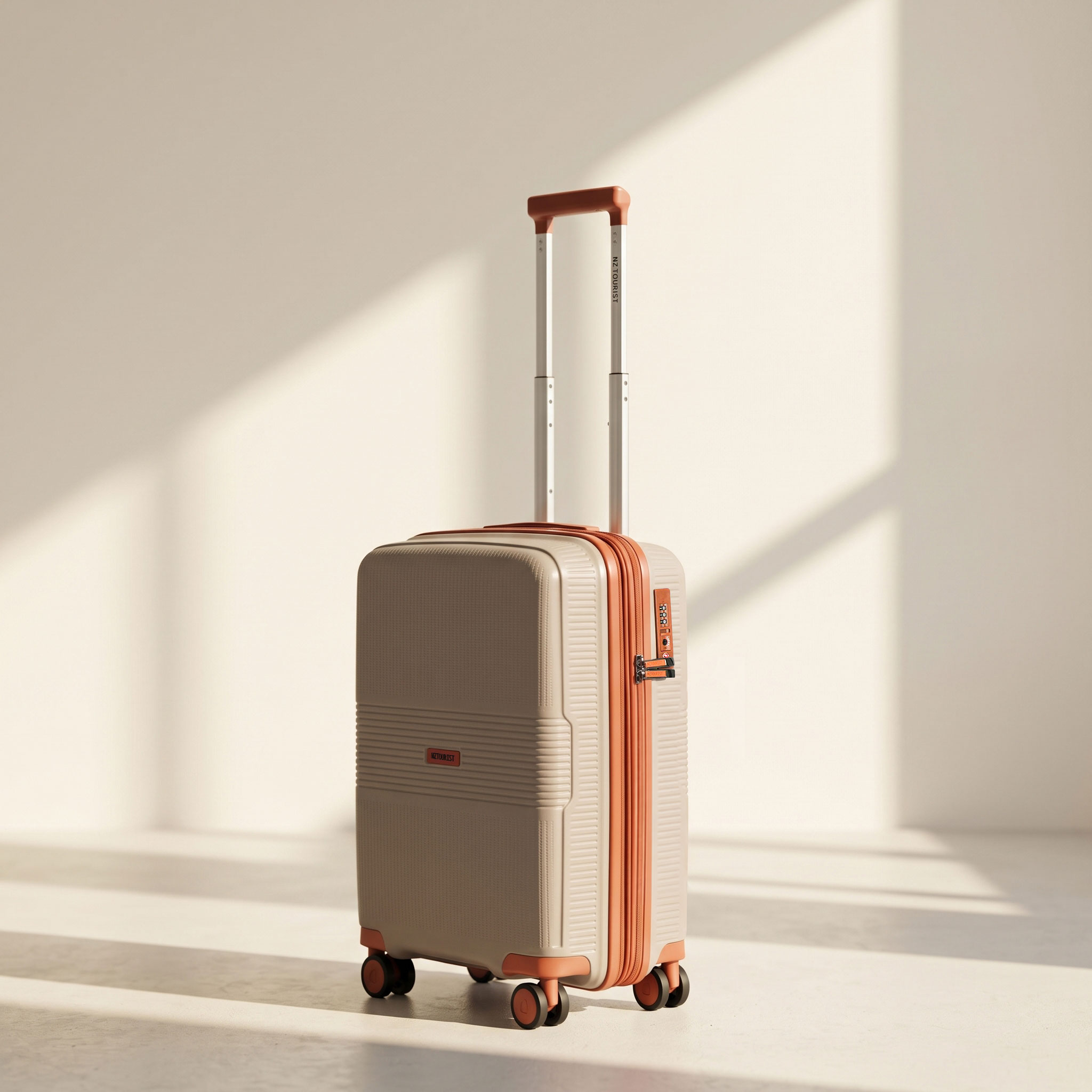 Small cabin suitcase in taupe with orange trim in a sunlit studio