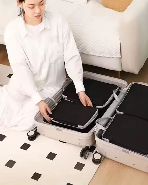 Woman packing black San Michelle packing cubes into an open suitcase