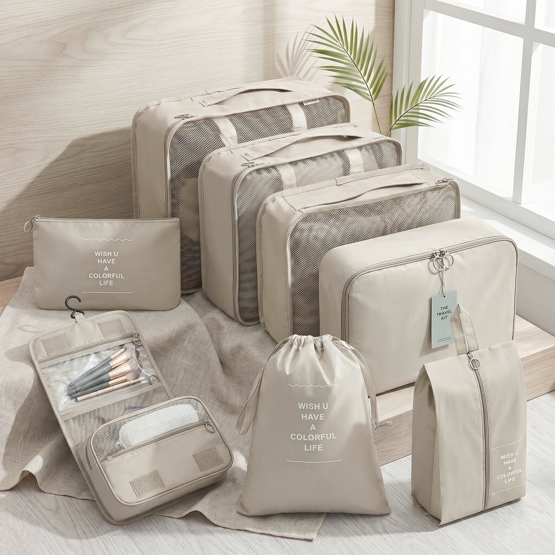 Beige packing cube and travel organiser set laid out on a bed